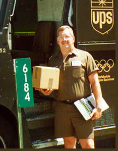 Photograph of a UPS driver standing next to a 911 Sign.